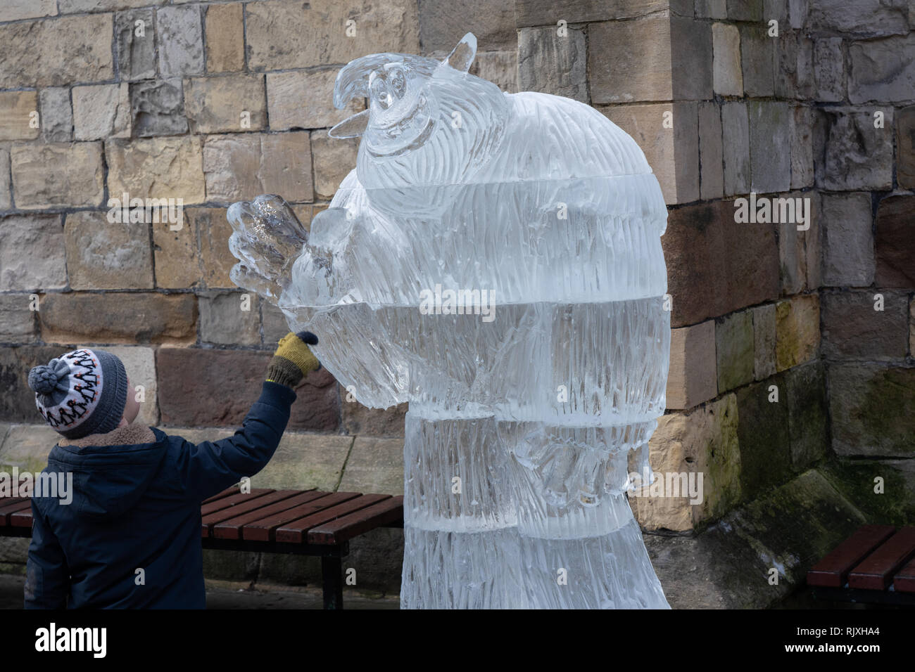 Jeune garçon touchant la sculpture sur glace MIGO Smallfoot, Myths et Legends, York Ice Trail, North Yorkshire, Angleterre, Royaume-Uni. Banque D'Images