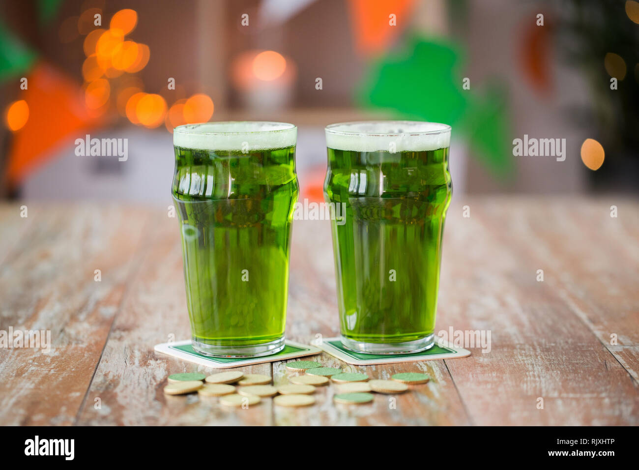 Verres de bière verte et de pièces d'or sur la table Banque D'Images