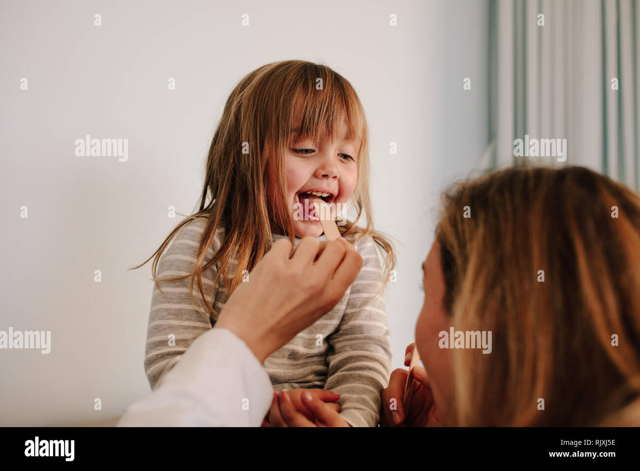 Femme médecin contrôler pour mal de gorge des patient. Petite fille ayant l'examen de la gorge avec abaisse-langue par un médecin pédiatrique. Banque D'Images