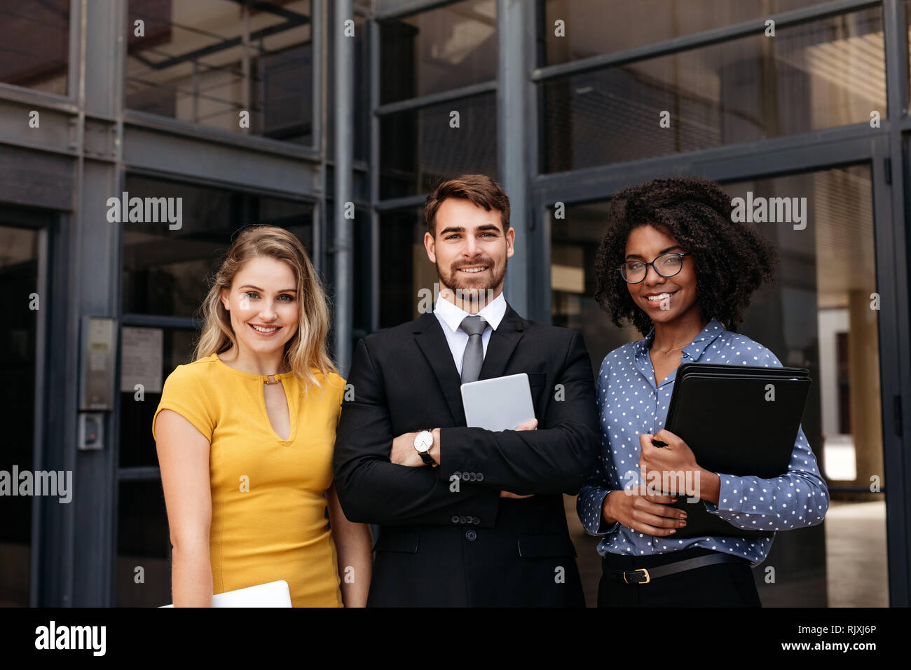 Équipe de jeunes professionnels unis dans l'avant du bâtiment. Groupe de gens d'affaires multi-ethnique dans un immeuble de bureaux de l'entreprise Banque D'Images