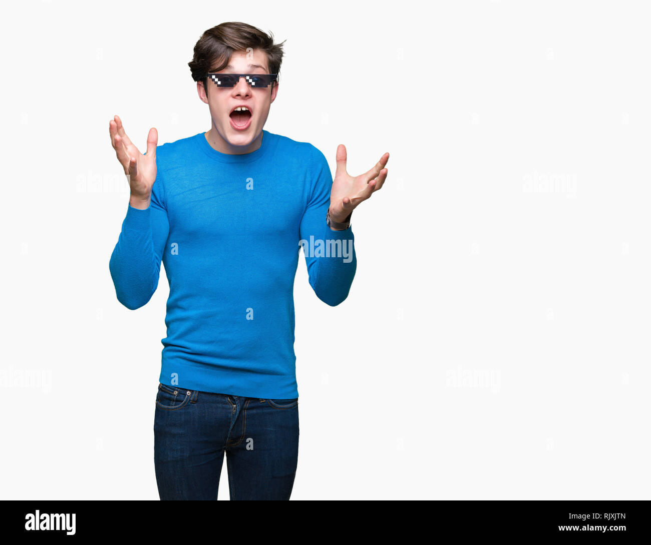 Jeune homme portant des lunettes plus drôle thug life fond isolé célébrant la folie et étonné pour le succès avec les bras levés et les yeux ouverts, screaming e Banque D'Images