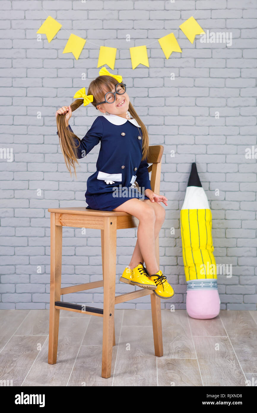 Cute school girl posing in studio shoot en uniforme d'habillement et de l'enveloppe sur fond de lettres ou gris mur de briques. Teen books et immense pe Banque D'Images