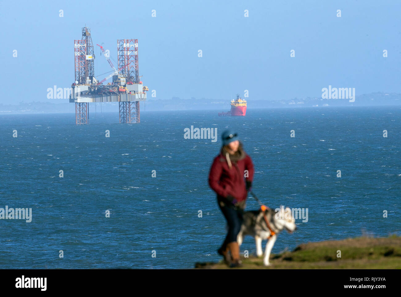 Une falaise dog walker passe l'ENSCO-72 drilling rig dans Poole Bay, au large de la côte du Dorset, où il s'enfonce un puits d'évaluation au nom de l'énergie Corallian pour évaluer le potentiel de réserves de pétrole dans la 'prospect' Coulter, au sud de l'actuel Wytch Farm oilfield. Banque D'Images