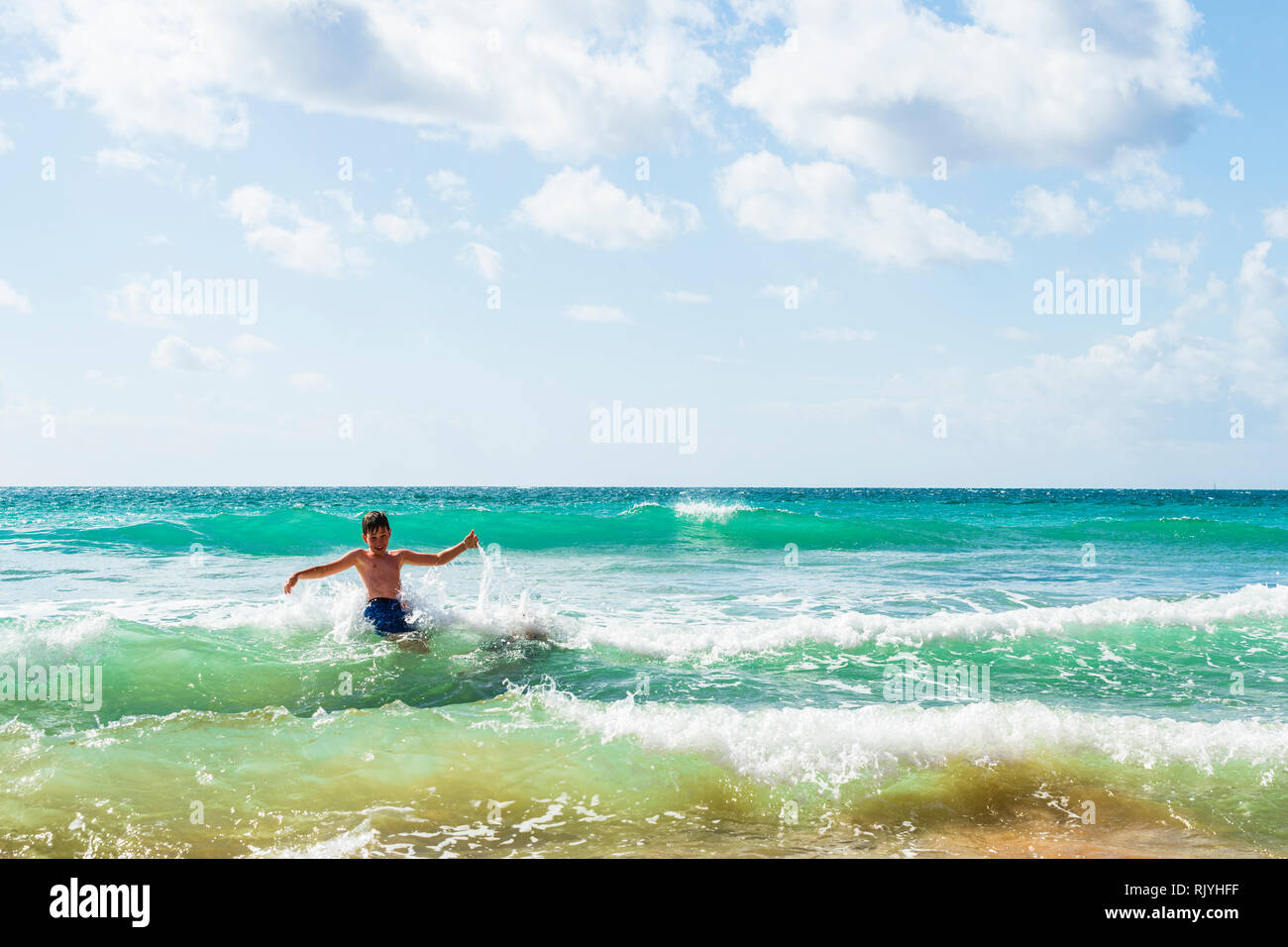 Boy with arms outstretched jouant en mer, Alvor, Algarve, Portugal, Europe Banque D'Images