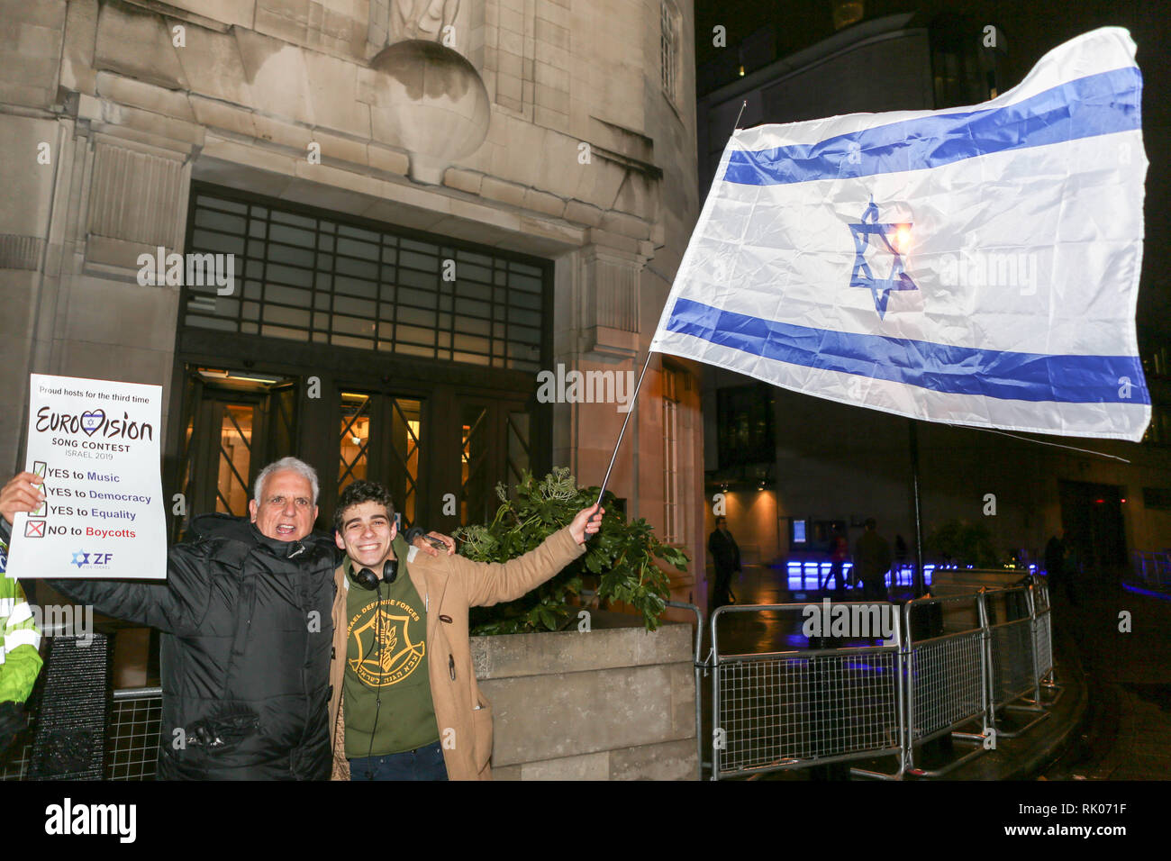 Londres, Royaume-Uni. 8 février 2019. Deux individus se tiennent devant la BBC la nuit, l'un portant un grand drapeau israélien et l'autre affichant une pancarte soutenant le concours Eurovision de la chanson. Deux groupes de manifestants devant la Broadcasting House manifestent pour et contre le concours Eurovision de la chanson 2019 qui se tient en Israël. 8 février 2019. Après la victoire de Netta Barzilai à l'édition 2018. Penelope Barritt/Alamy Live News Banque D'Images