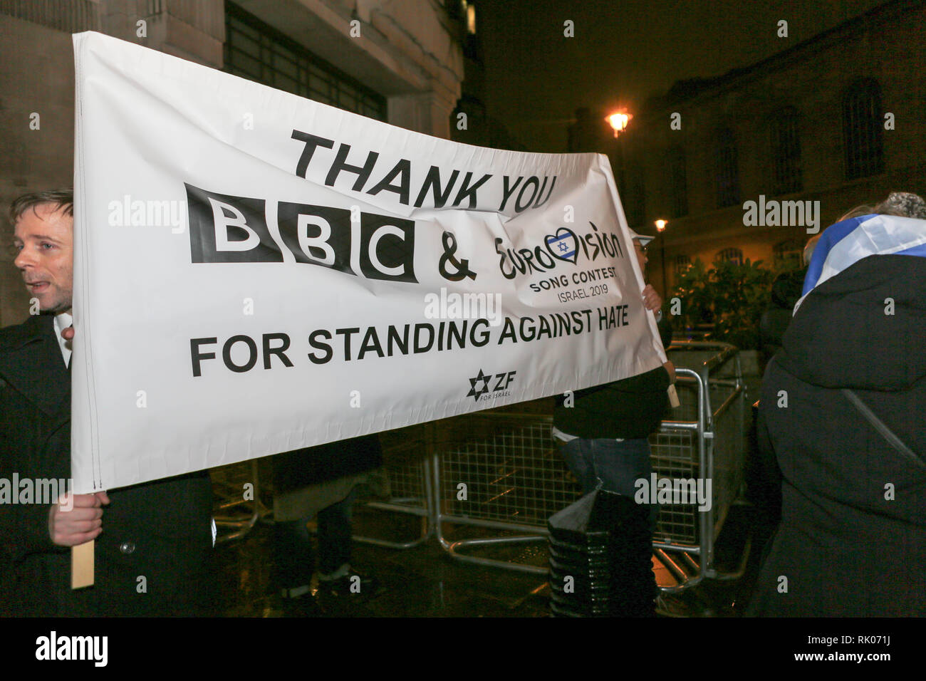 Londres, Royaume-Uni. 8 février 2019. Un groupe de manifestants tient une grande bannière lisant MERCI BBC & Eurovision Song Contest POUR S'ÊTRE DRESSÉS CONTRE LA HAINE ZF lors d'un rassemblement public nocturne. La bannière comporte une étoile de David et les initiales ZF, faisant probablement référence à la Fédération sioniste. Deux groupes de manifestants devant la Broadcasting House manifestent pour et contre le concours Eurovision de la chanson 2019 qui se tient en Israël. 8 février 2019. Après la victoire de Netta Barzilai à l'édition 2018. Crédit : Penelope Barritt/Alamy Live News Banque D'Images