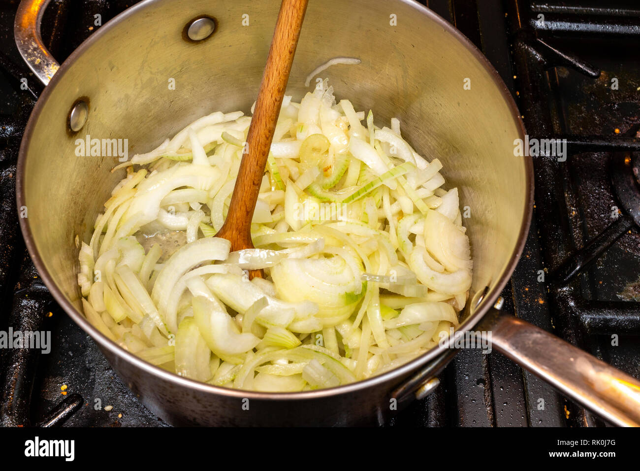 Faire frire les oignons dans une casserole sur une cuisinière. Banque D'Images