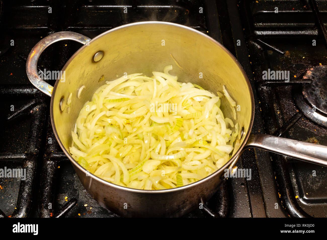 Faire frire les oignons dans une casserole sur une cuisinière. Banque D'Images