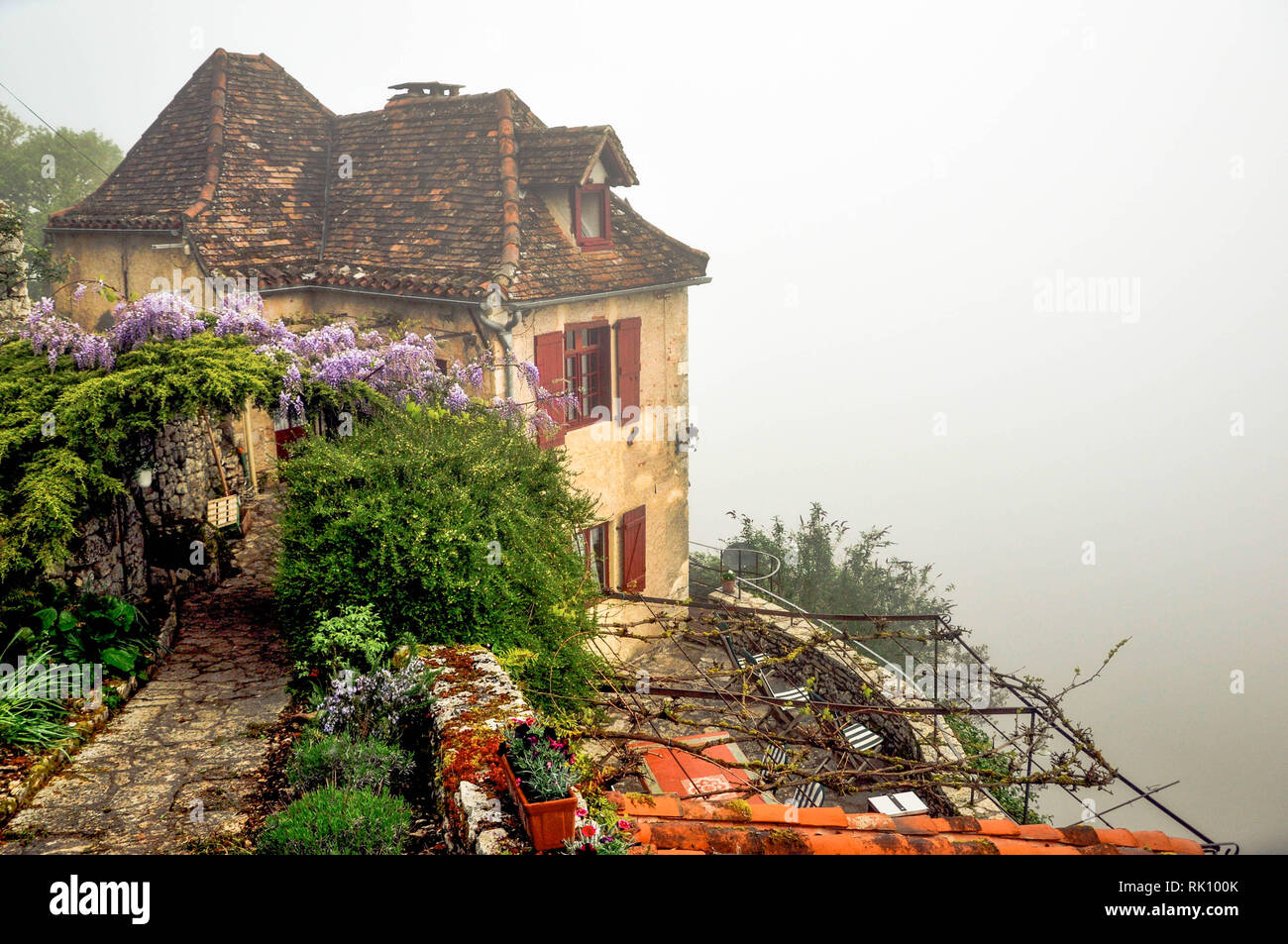 Des siècles old stone house se trouve dans le brouillard au bord de la falaise surplombant la rivière Lot dans le sud-ouest de la France ville médiévale de Saint Cirque Lapopie. Banque D'Images