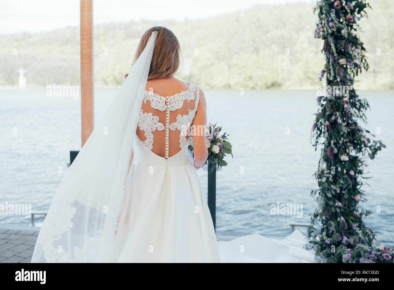 La mariée tient un bouquet dans ses mains près de l'arche de mariage Banque D'Images
