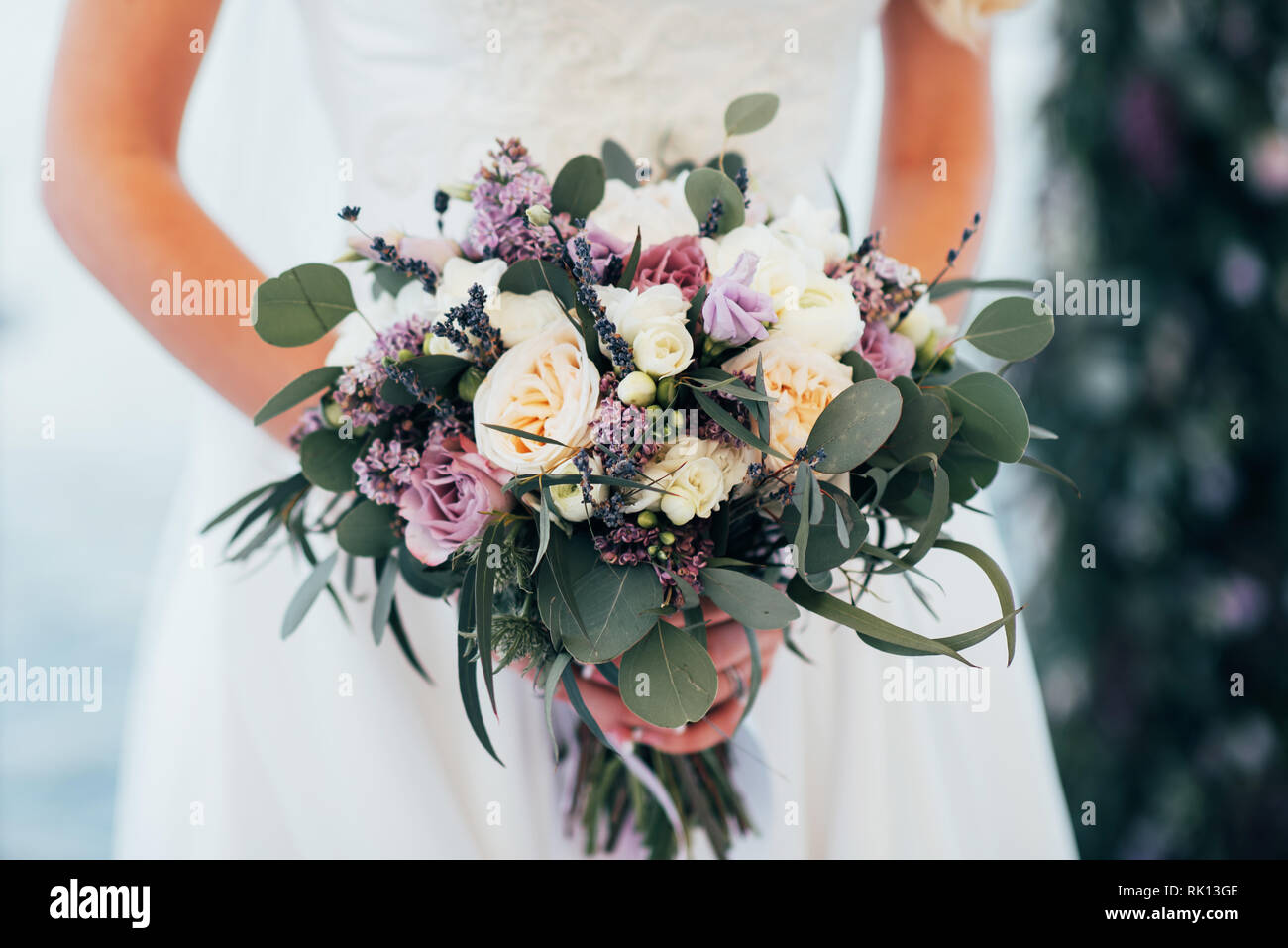 La mariée tient un bouquet dans ses mains près de l'arche de mariage Banque D'Images