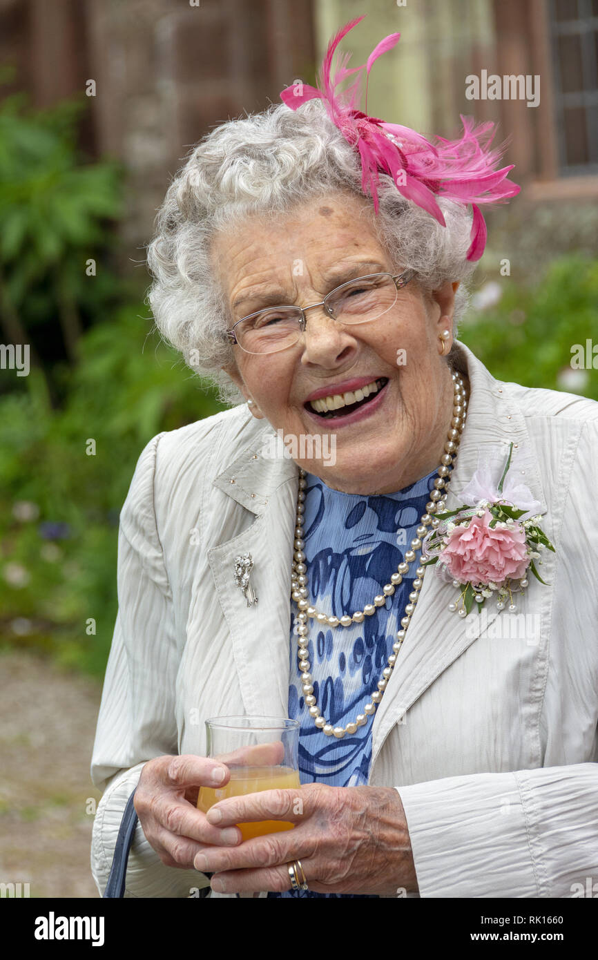 Habillé d'une vieille dame heureuse de déguster une boisson Banque D'Images