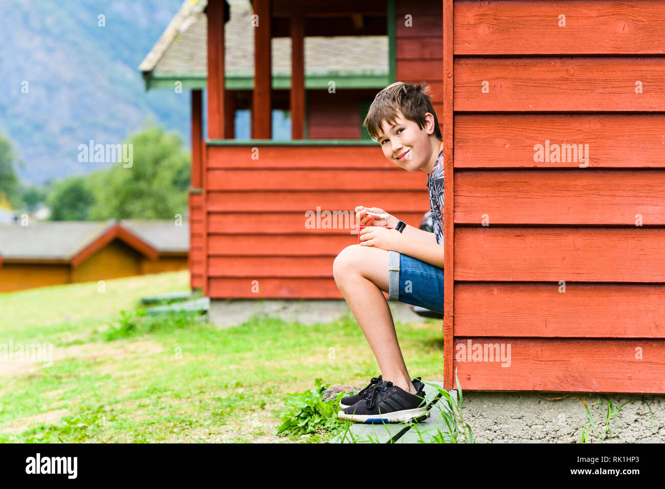 Portrait de garçon assis sur les marches du chalet de vacances, Flam, Norvège, Europe Banque D'Images