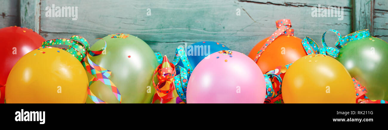 Bannière de fête avec une rangée de ballons colorés et de rubans d'affilée contre l'ancien fond de bois Banque D'Images