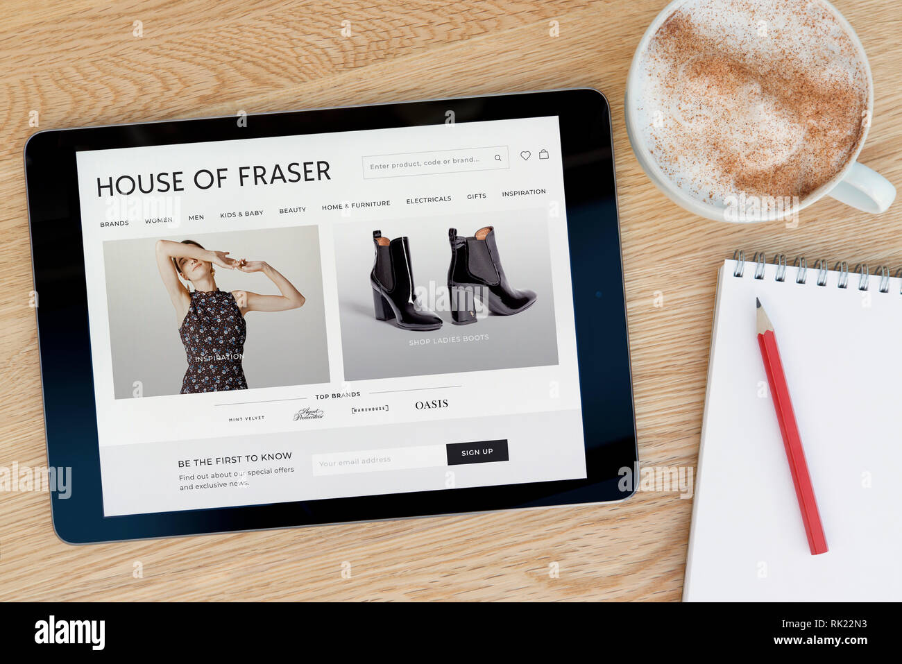 La House of Fraser site web présente sur un iPad tablet device qui repose sur une table en bois à côté d'un bloc-notes (usage éditorial uniquement). Banque D'Images