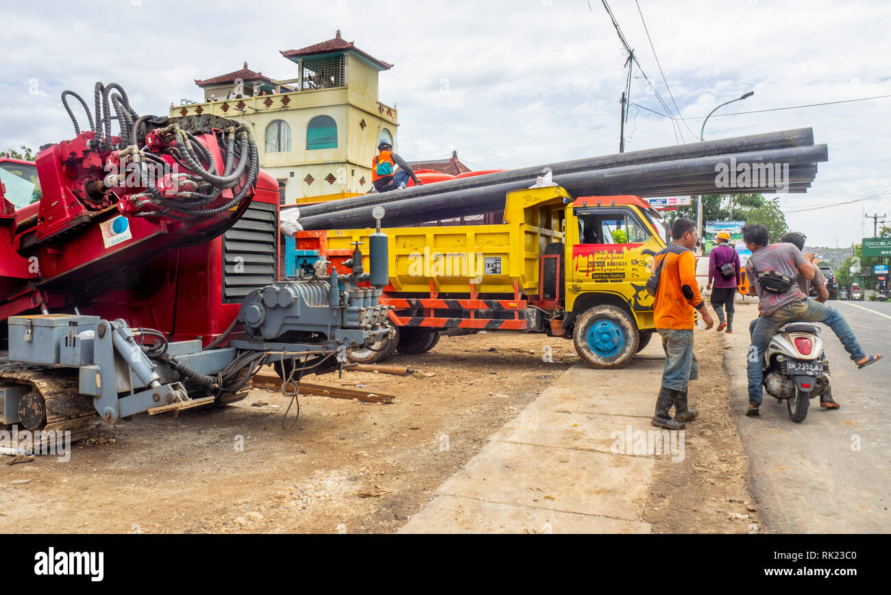 Ouvriers dans une cour du déchargement d'un camion, les tuyaux et l'équipement lourd, à Jimbaran, Bali, Indonésie Bali Indonésie.. Banque D'Images