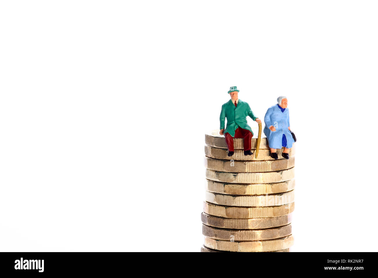 L'image conceptuelle diorama d'une figure miniature à la retraite couple assis sur une pile de pièces en livres Banque D'Images