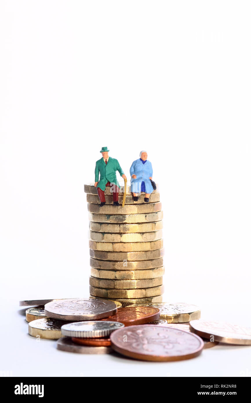 L'image conceptuelle diorama d'une figure miniature à la retraite couple assis sur une pile de pièces en livres Banque D'Images