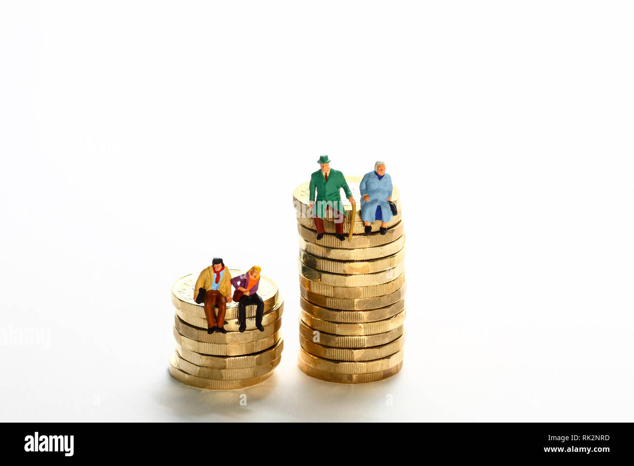 Image conceptuelle diorama d'une figure miniature à la retraite couple et un jeune couple s'est assis sur une pile de pièces de livre Banque D'Images
