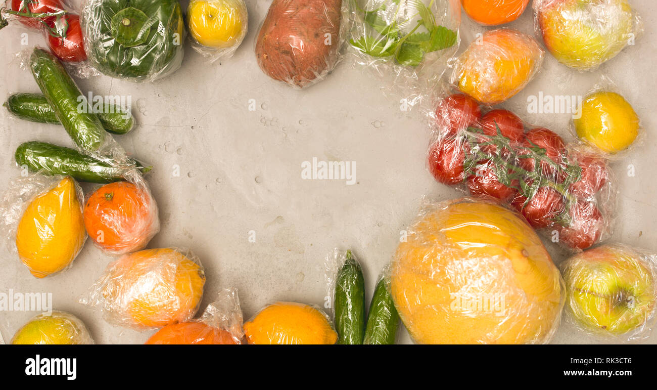 Beaucoup de différents fruits et légumes sont emballés dans un sachet en plastique, paniers sur fond de béton Banque D'Images