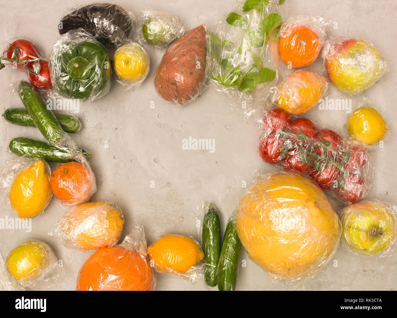 Beaucoup de différents fruits et légumes sont emballés dans un sachet en plastique, paniers sur fond de béton Banque D'Images