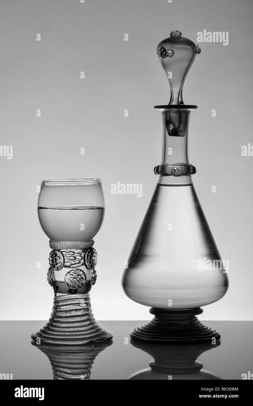 L'âge moyen rummer wine glass et la bouteille sur le fond blanc. Le noir et blanc, monochrome photo. Banque D'Images