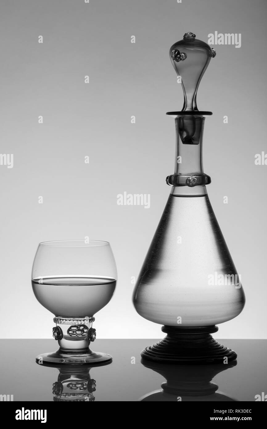 L'âge moyen rummer wine glass et la bouteille sur le fond blanc. Le noir et blanc, monochrome photo. Banque D'Images