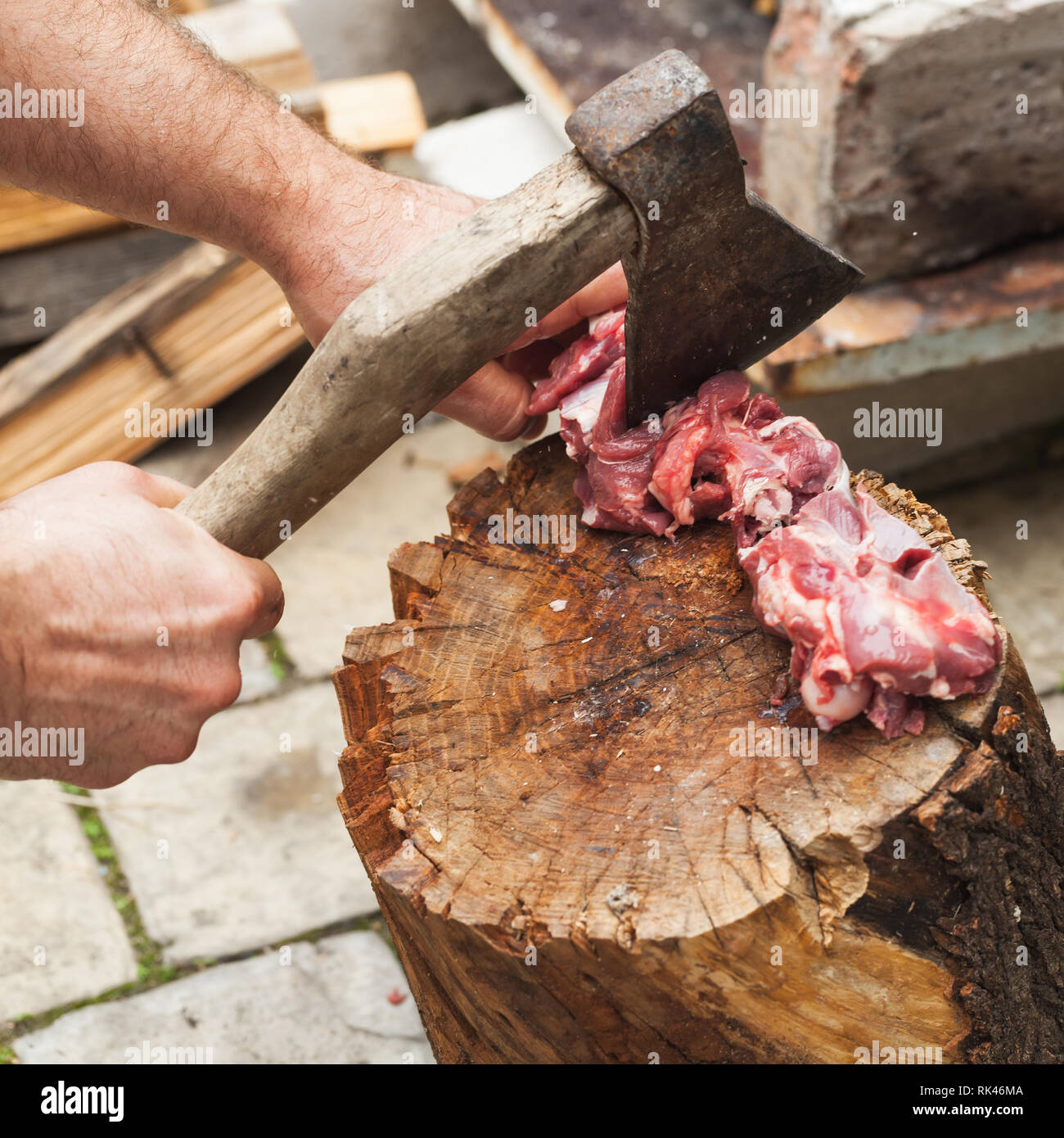 Découpe de la viande d'agneau crue sur log, cuire les mains avec ax, close-up photo Banque D'Images