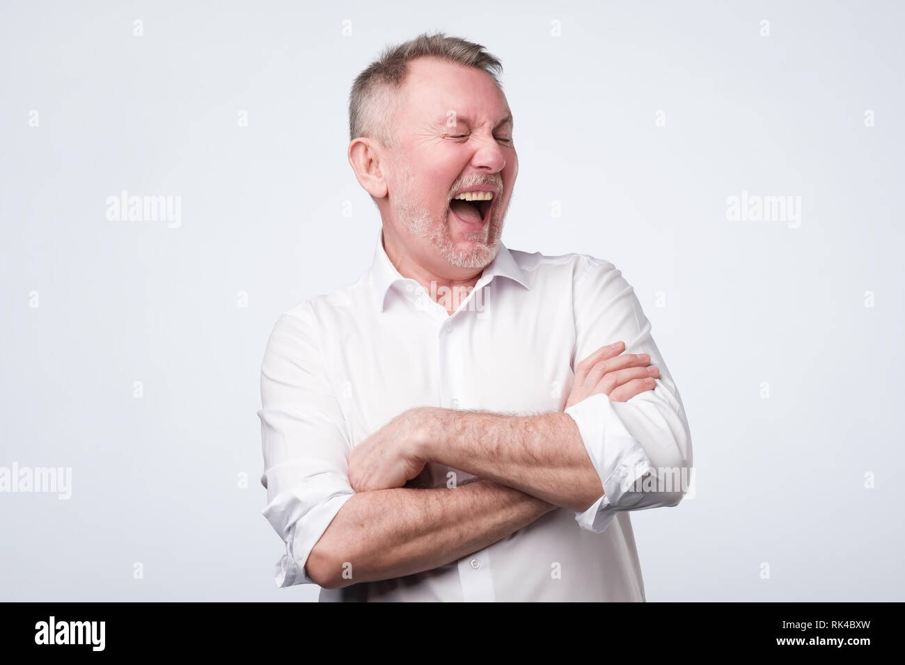 Smiling homme âgé en chemise blanche debout à studio. Banque D'Images