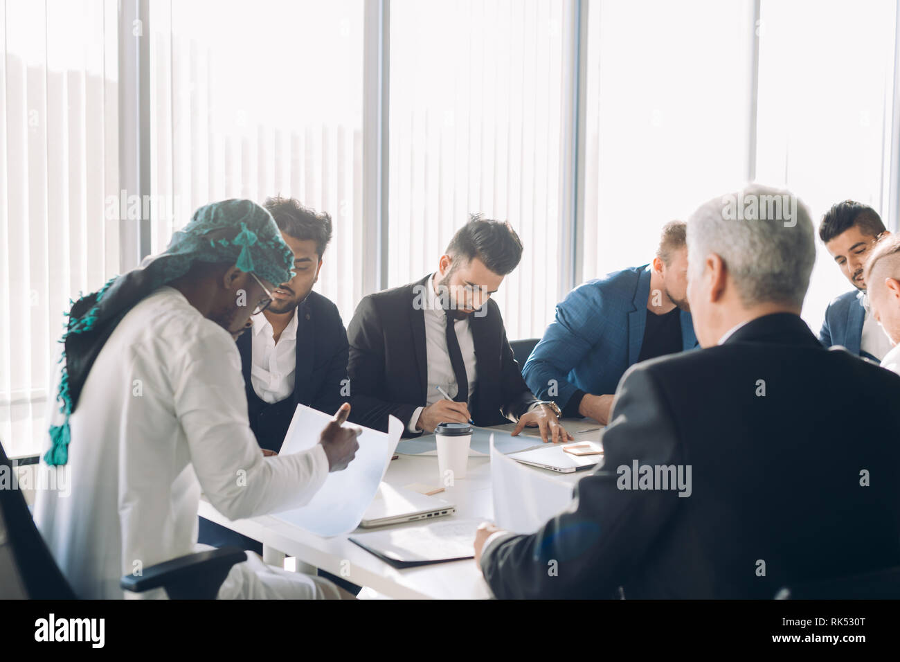 Investisseur arabe en blanc et gutra candura nationale sur la stratégie financière de l'entreprise tête de discuter avec son multirucial sexe masculin au cours d'une réunion Banque D'Images