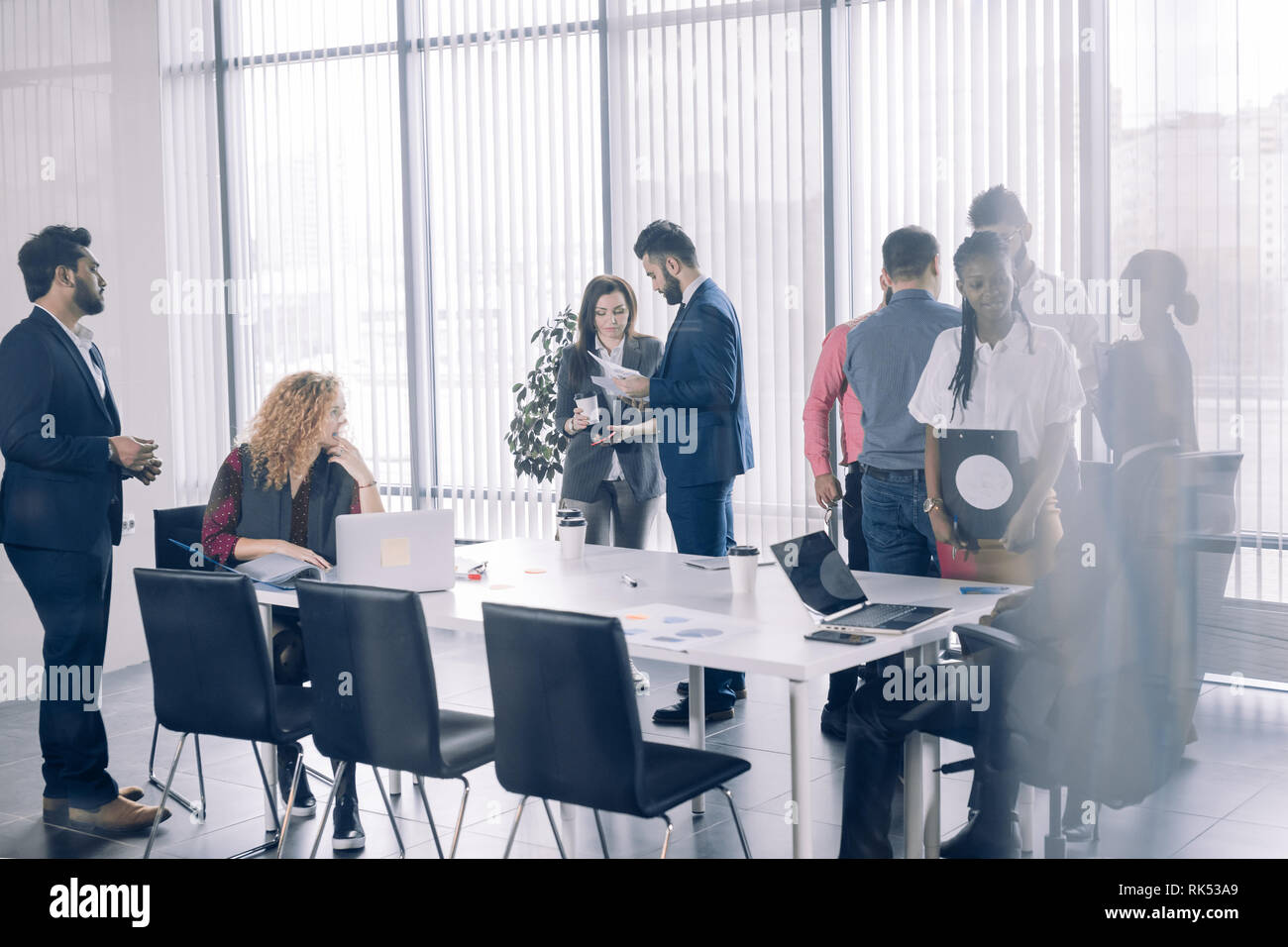 Les gens d'affaires diversifié multiraciale positive officielles et des vêtements décontractés sont sujets à discuter et partager des impressions tout en se tenant dans conferenc Banque D'Images