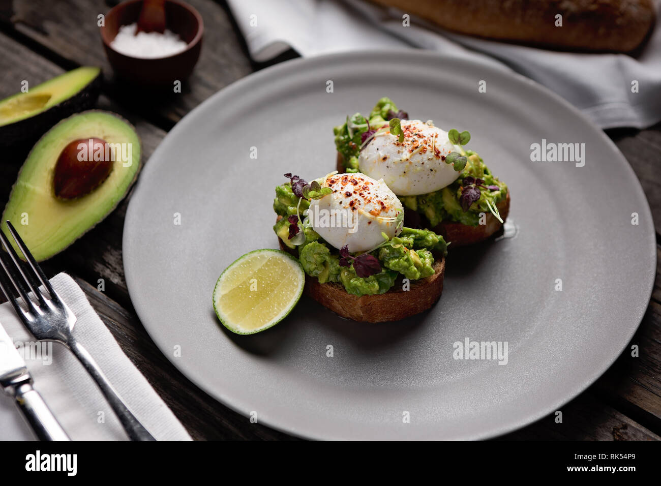 Deux œufs pochés sur toast à l'avocat d'épices sur une plaque ronde gris Banque D'Images