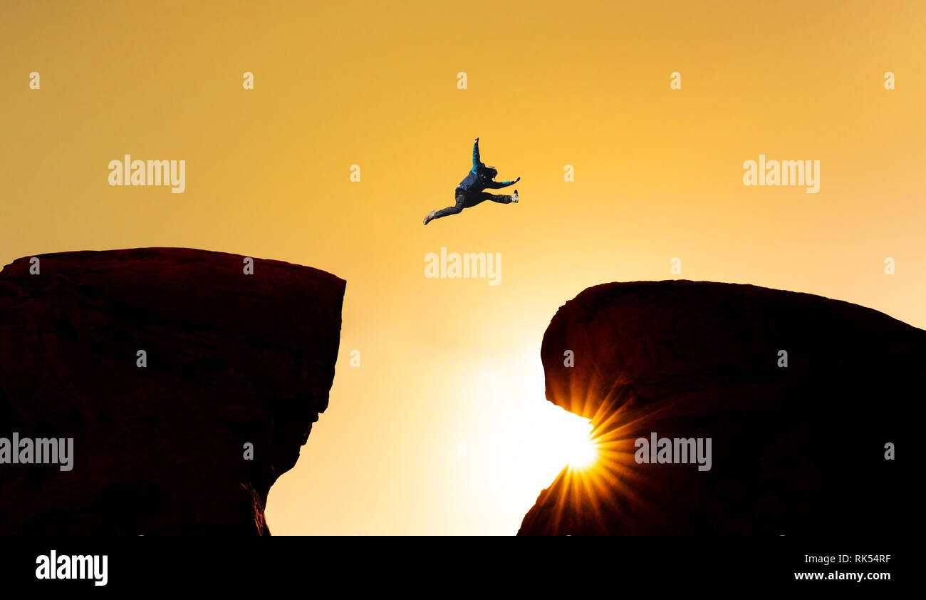 Défi, le risque et la liberté concept. Une Silhouette man jumping over précipice crossing cliff Banque D'Images