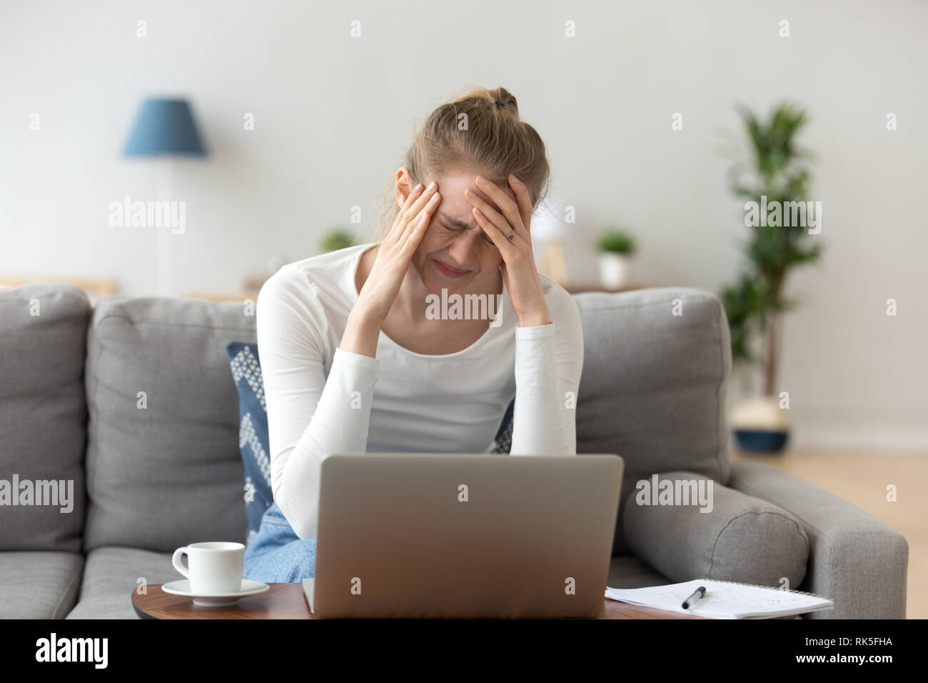 Souligné assez jeune femme se sentir mal de tête après de longs travaux d'ordinateur portable Banque D'Images
