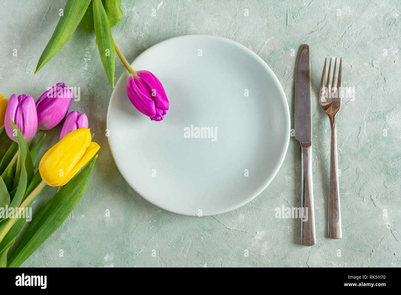 Valentines Day, dîner romantique concept. Fleur de tulipe, ensemble de plats avec des couverts. Banque D'Images