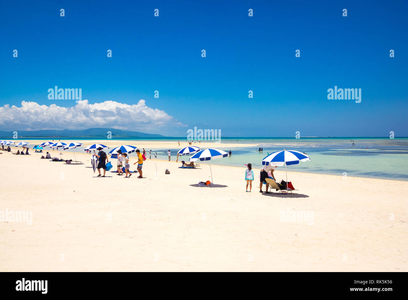 Les touristes et les parasols de plage bleu et blanc sur Kondoi Beach, Île Taketomi Island (Île Taketomi-jima), îles Yaeyama, Okinawa Prefecture, Japan. Banque D'Images