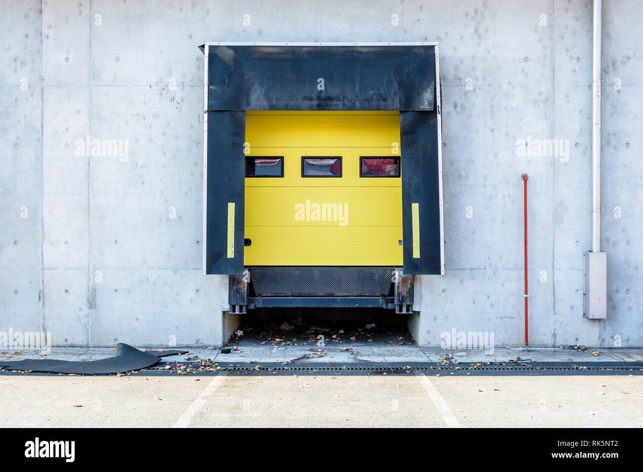 Vue de face d'une baie de chargement de camions avec des joints en caoutchouc dans le mur de béton d'un entrepôt dans la banlieue de Paris, France, avec un rouleau jaune s Banque D'Images