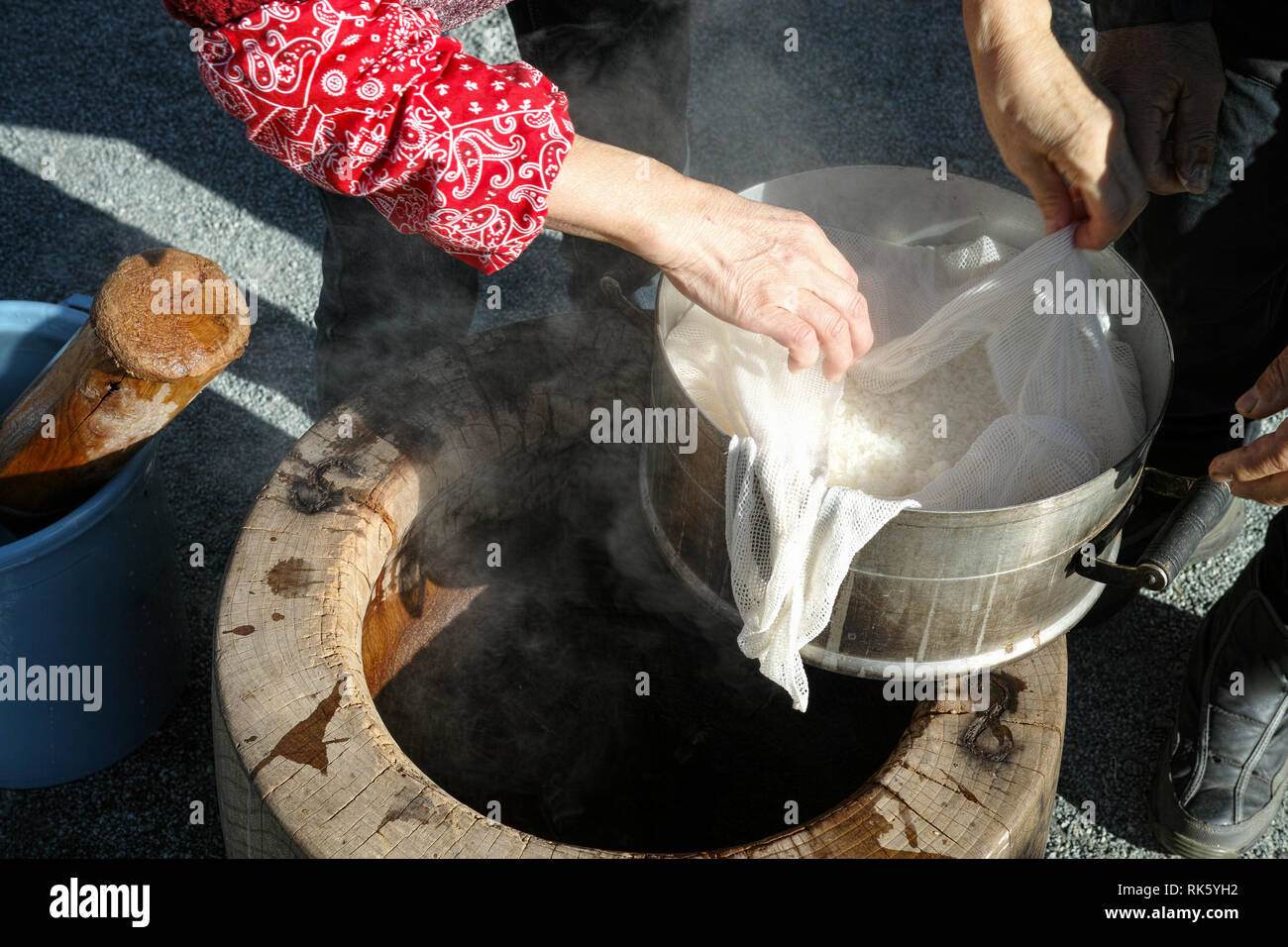 Un couple de personnes âgées à la recherche sur le riz (mochigome utilisé pour faire mochi) avant de le mettre le grand mortier Banque D'Images