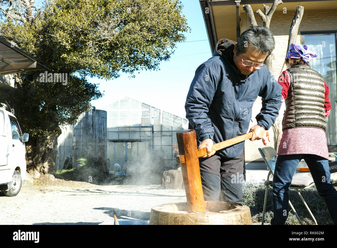Un homme plus âgé faisant mochi dans son jardin avec sa famille autour de lui Banque D'Images