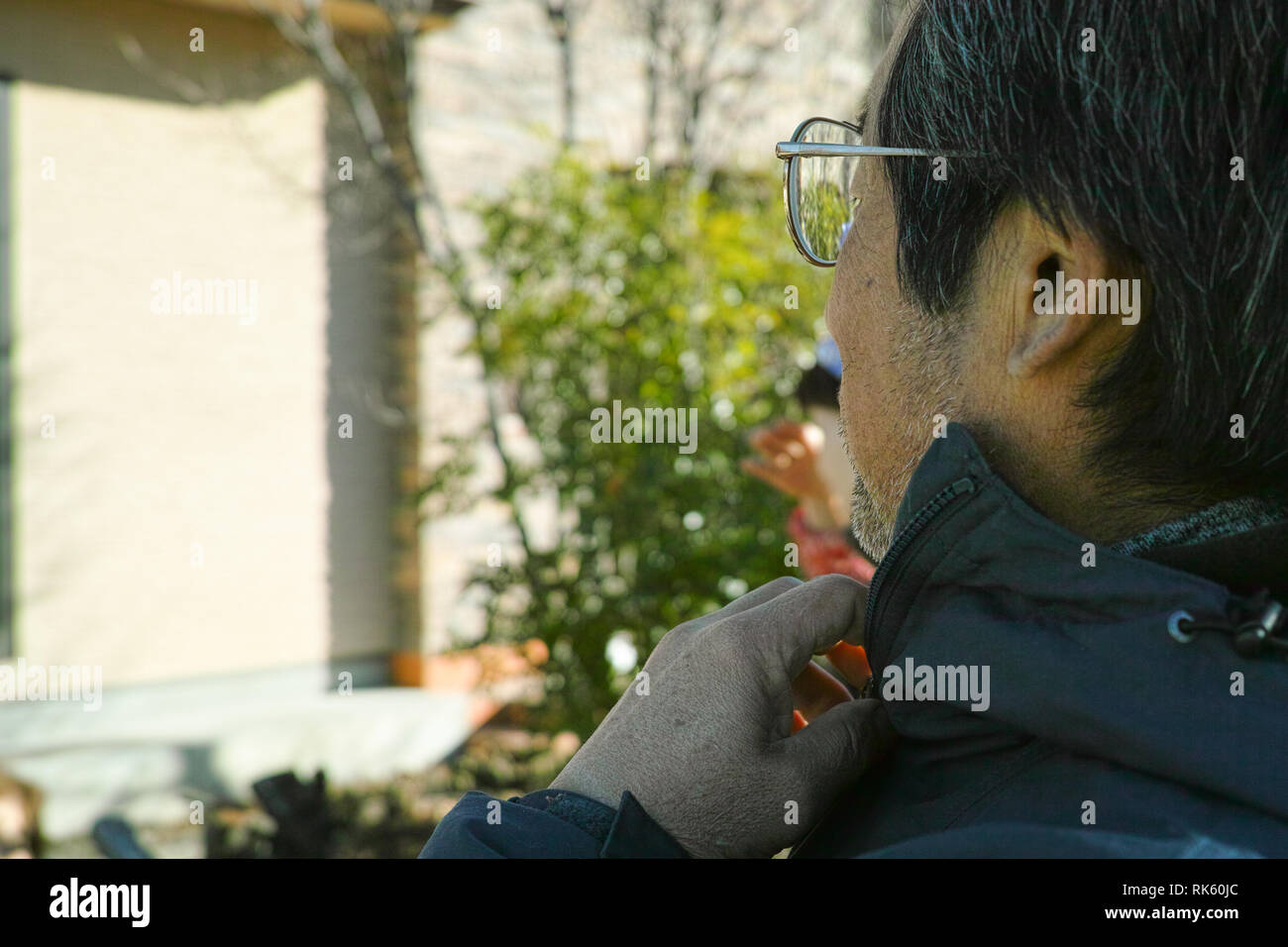 Un aîné monsieur avec les cheveux gris trier son manteau collier dans le froid Banque D'Images