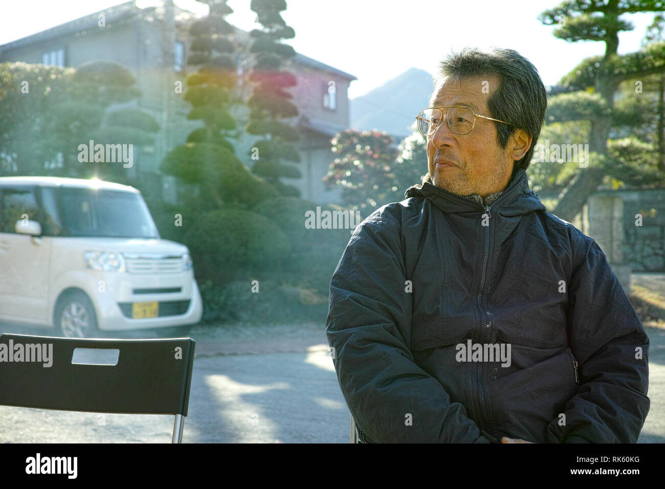 Un beau frère homme japonais assis en face de sa voiture dans le froid Banque D'Images