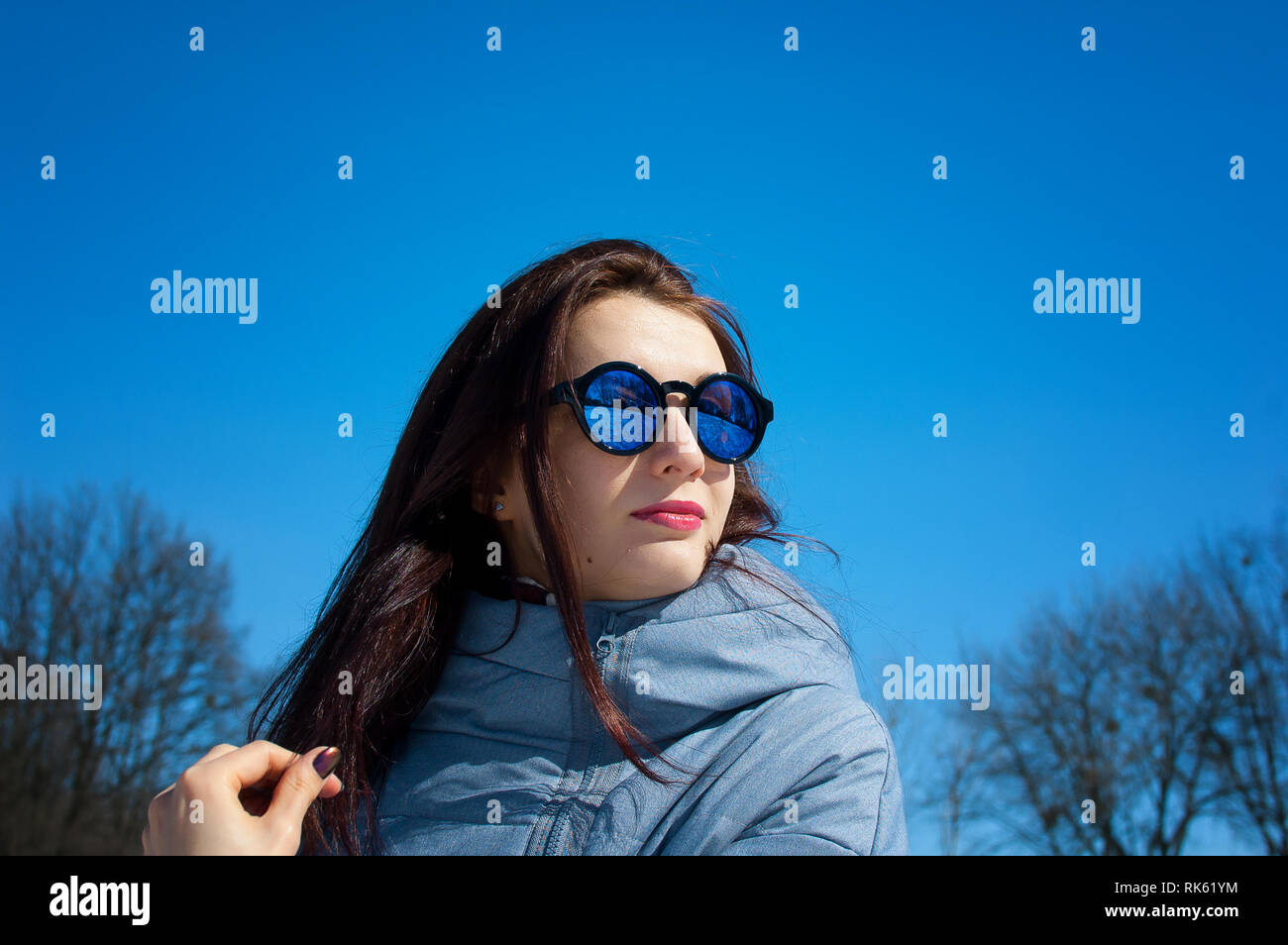 Portrait de la belle jeune femme avec des lunettes de soleil miroir en  plein air au cours de ciel bleu au début du printemps Photo Stock - Alamy
