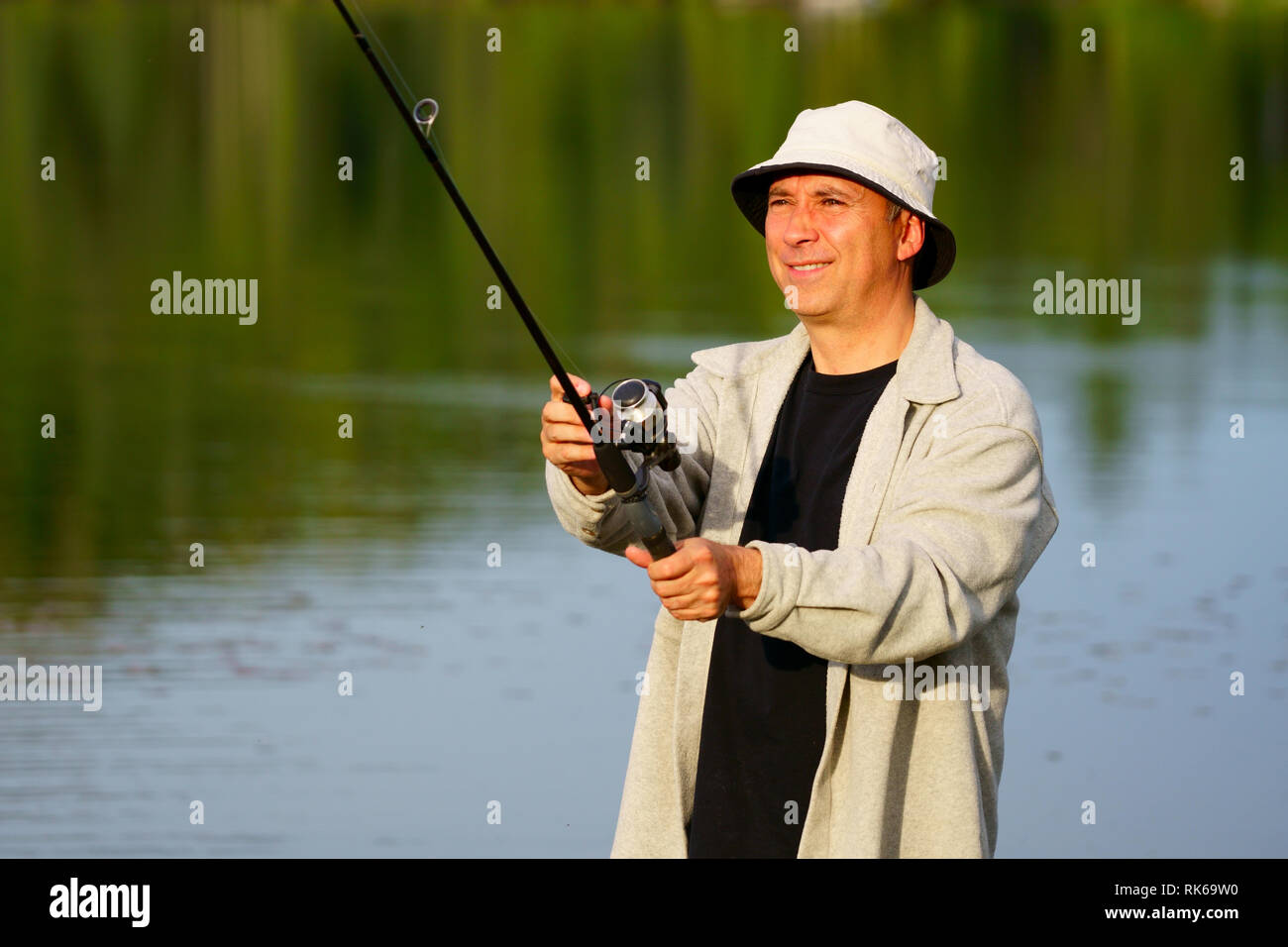 Portrait d'un pêcheur de race blanche, 50 ans, au bord du lac au coucher du soleil. Banque D'Images