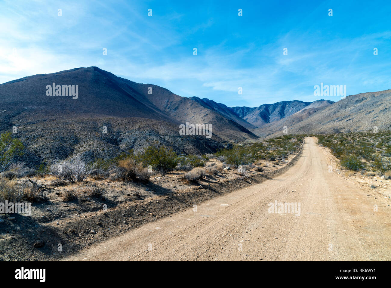 Fire route menant en désert aride montagne sous ciel bleu avec des nuages. Banque D'Images