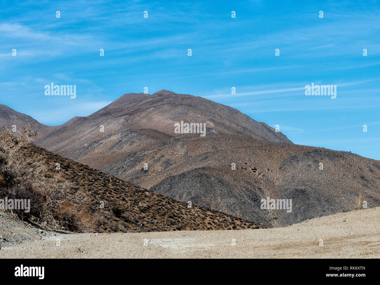 La recherche à travers les montagnes arides du désert sec sous ciel bleu. Banque D'Images