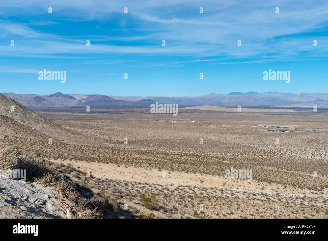 Donnant sur une vallée dans le désert de Mojave, où la végétation est clairsemée et de montagnes stériles sous ciel bleu avec des nuages. Banque D'Images