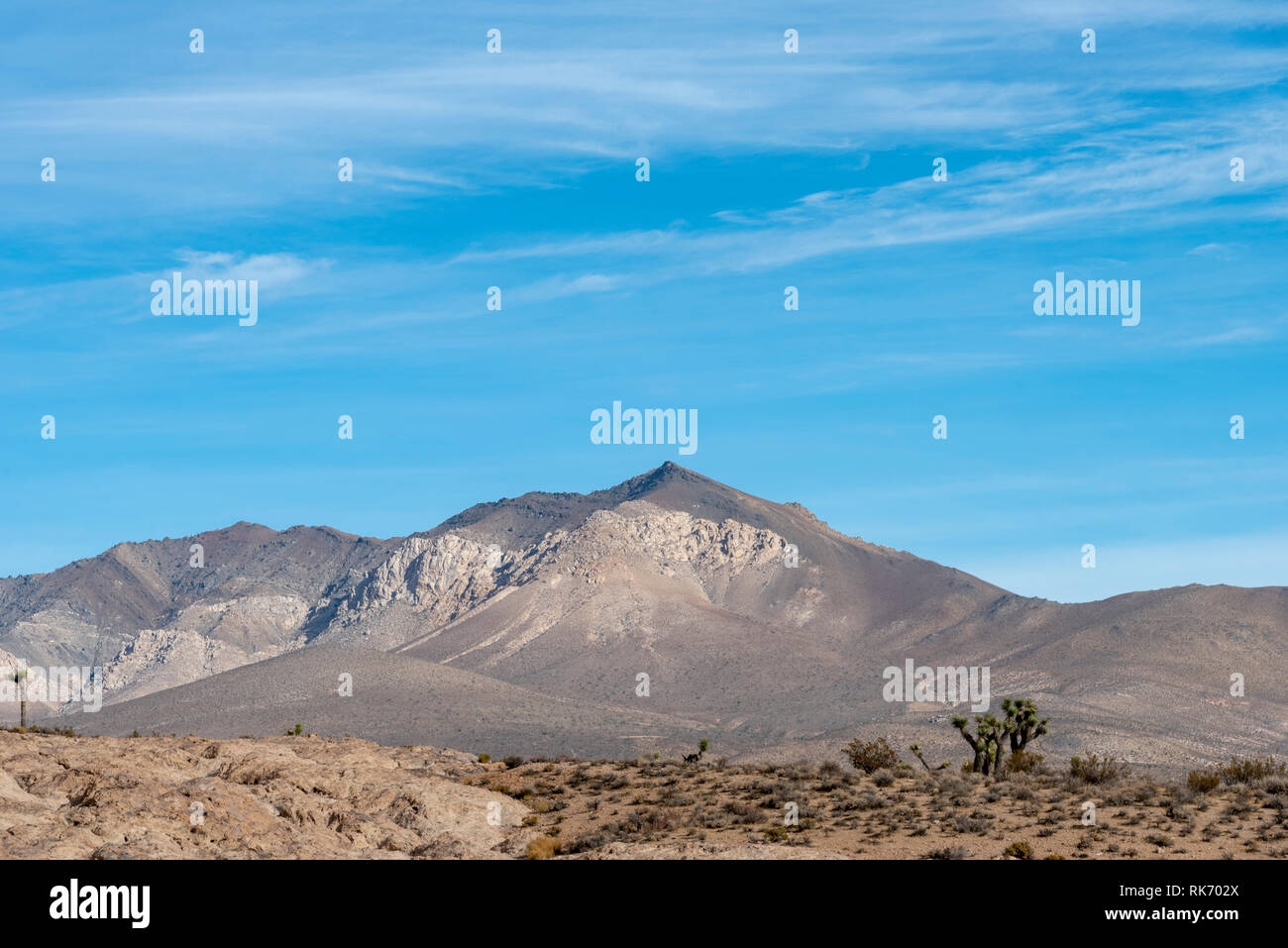 Ravine et rocky le désert d'un côté et le désert de sable de l'autre côté jusqu'à haute montagnes stériles sous ciel bleu avec des nuages blancs. Banque D'Images