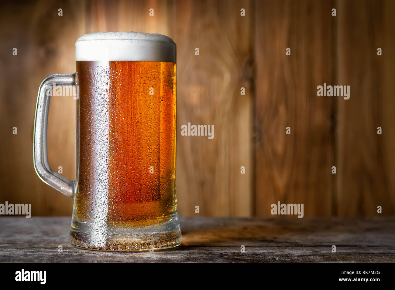 La lumière froide de la bière en tasse avec gouttes d'eau sur la table en bois Banque D'Images