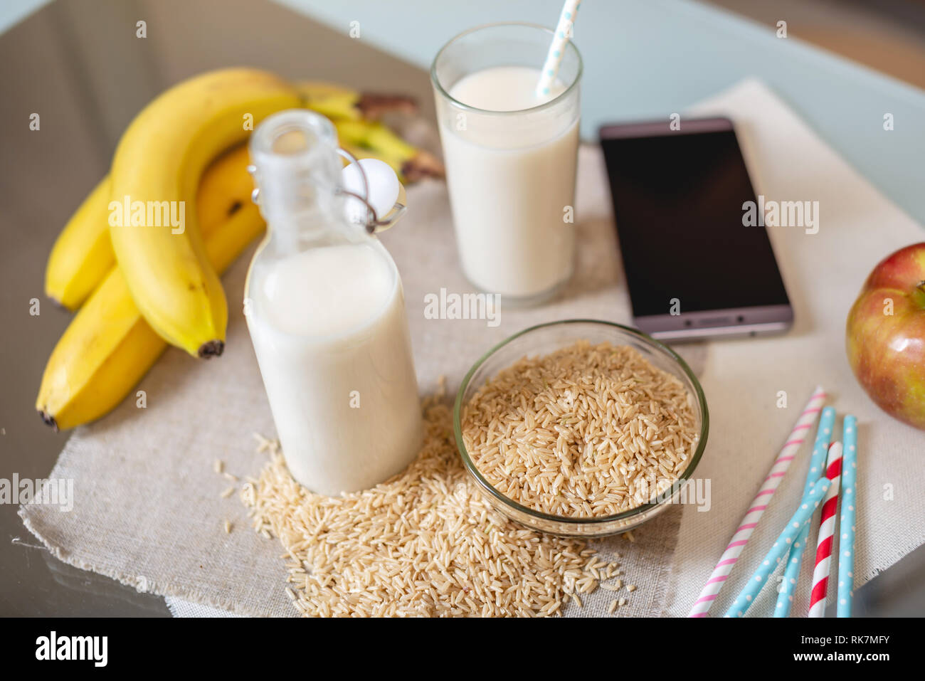 Le lait de riz dans une tasse en verre et des fruits avec des grains de riz sur la table. Produit végétarien sain de régime Banque D'Images