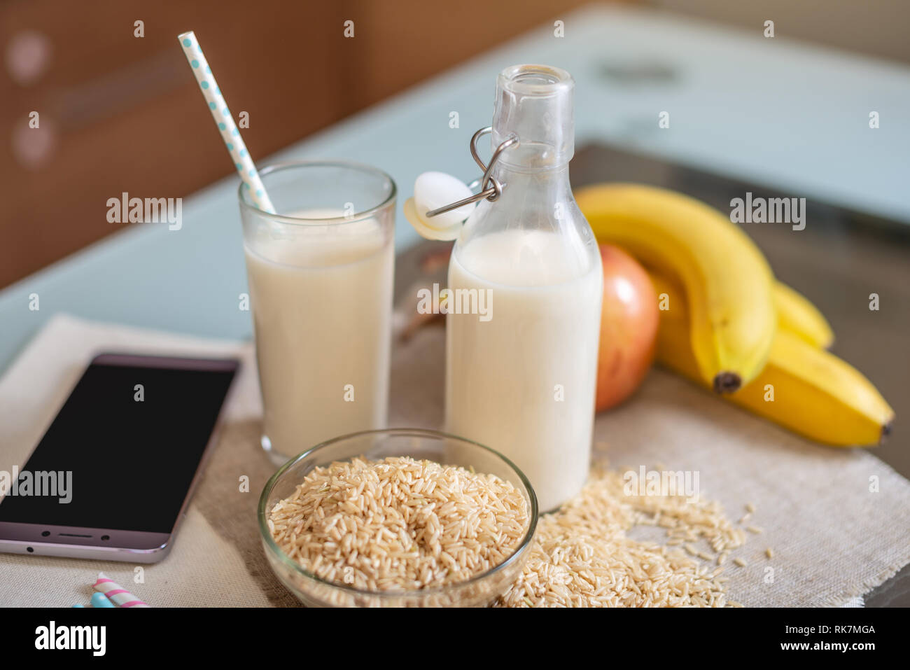 Le lait de riz dans une tasse en verre et des fruits avec des grains de riz sur la table. Produit végétarien sain de régime Banque D'Images